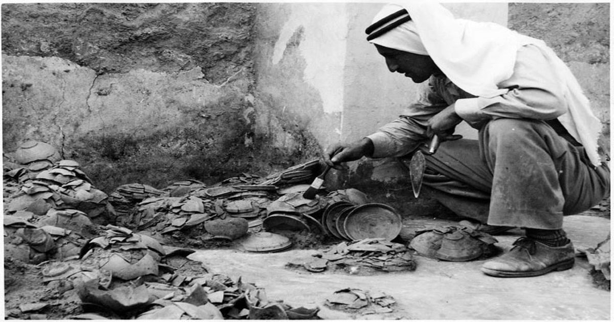 Photographie historique de fouilles à Qumrân montrant la découverte et le tri de fragments archéologiques liés au site des Manuscrits de la mer Morte.