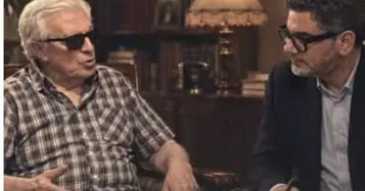 Deux hommes en interview l'un avec des lunettes noirs et l'autre posant des questions.