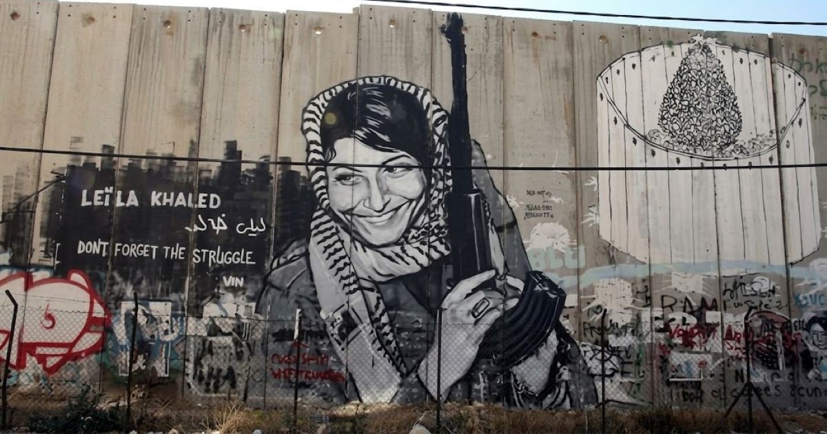 Fresque murale sur le mur de séparation représentant Leïla Khaled coiffée d'un keffieh et tenant un fusil avec le texte "Leïla Khaled Don't Forget The Struggle