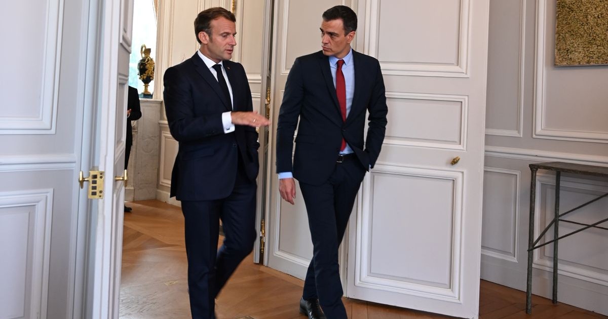 Le président français Emmanuel Macron et le Premier ministre espagnol Pedro Sánchez marchant et discutant dans un salon officiel..