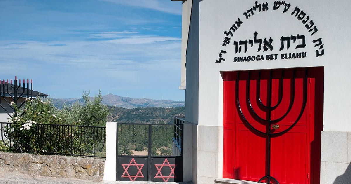 Façade de la synagogue Beit Eliyahou de Belmonte, au Portugal, avec ses portes rouges ornées d’une Ménora, ses étoiles de David et ses inscriptions hébraïques.
