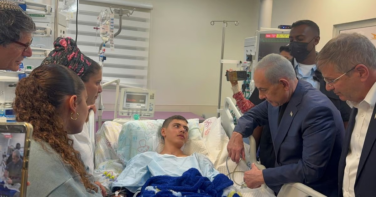 Le Premier ministre Benjamin Netanyahou au chevet d'un jeune adolescent blessé hospitalisé en Israël, entouré des proches et de médecins.
