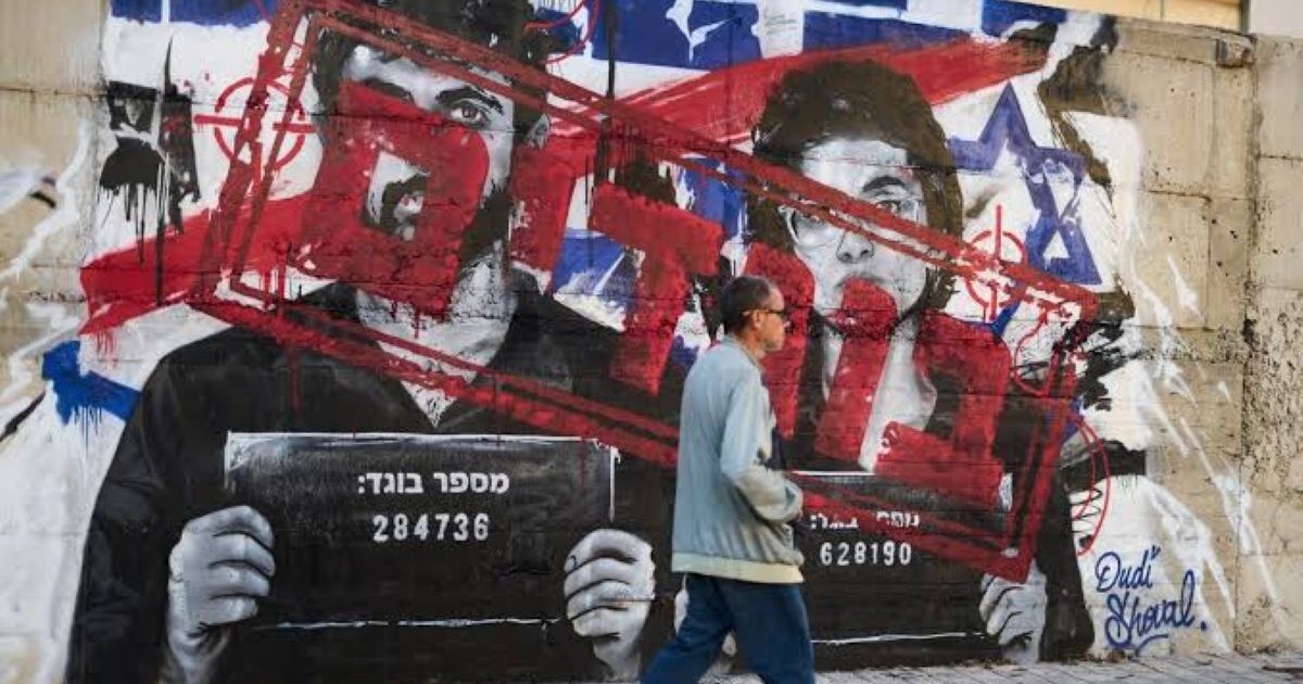 Un passant marche devant un grand graffiti mural, en Israël, représentant les réalisateurs Rachel Szor et Yuval Abraham.