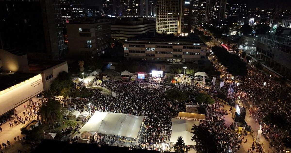 Vue aérienne nocturne d’une foule réunie sur la place des Otages à Tel-Aviv.
