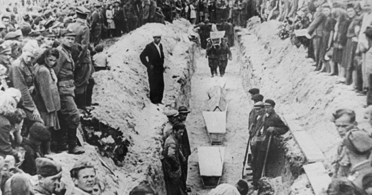 Des personnes en deuil se rassemblent autour d'une étroite tranchée au moment où on descend les cercueils des victimes du pogrom dans la fosse commune.